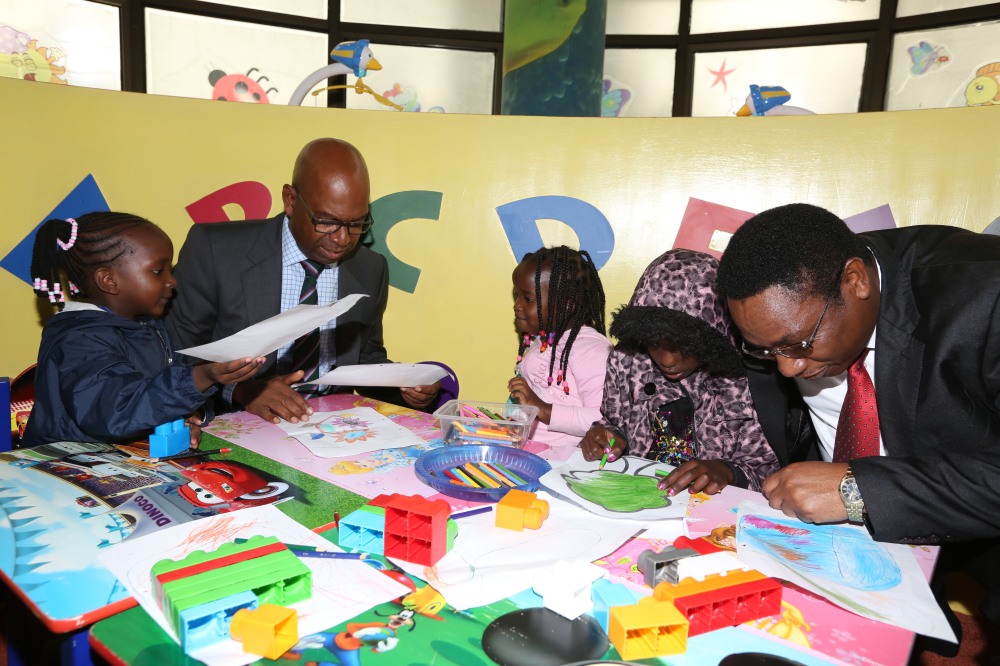 Safaricom CEO Bob Collymore and Dr Kioko helping children at the Safaricom creche with their artwork.